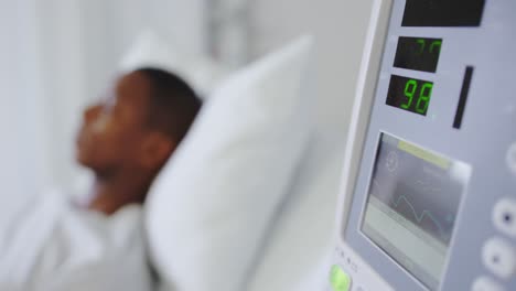 close-up of medical monitor with african american male patient in the ward at hospital