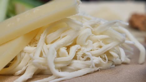 close up of a block of parmesan cheese and shredded string cheese