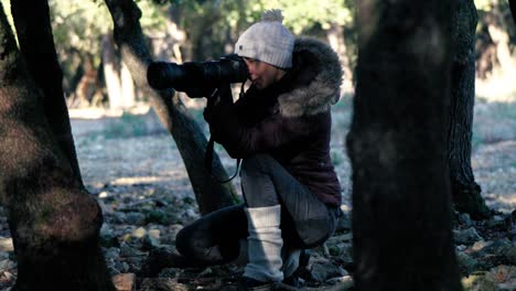 slow motion shot of a wildlife photographer hiding between trees