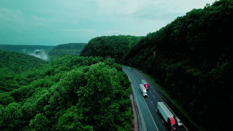 semi truck convoy traversing scenic forest highway through rock cut ridge tenneessee