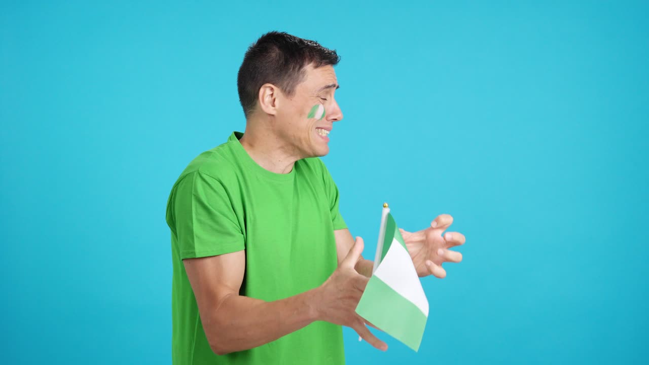 Nervous man cheering for Nigeria during a match looking away