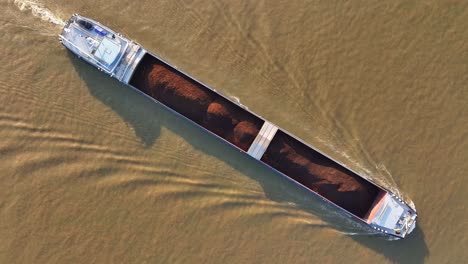 large cargo vessel, tarpaulin covered goods, murky river waters, aerial