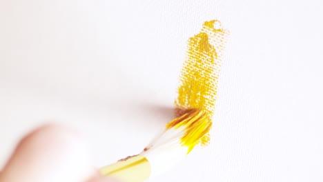 painting with a gold brush on white canvas