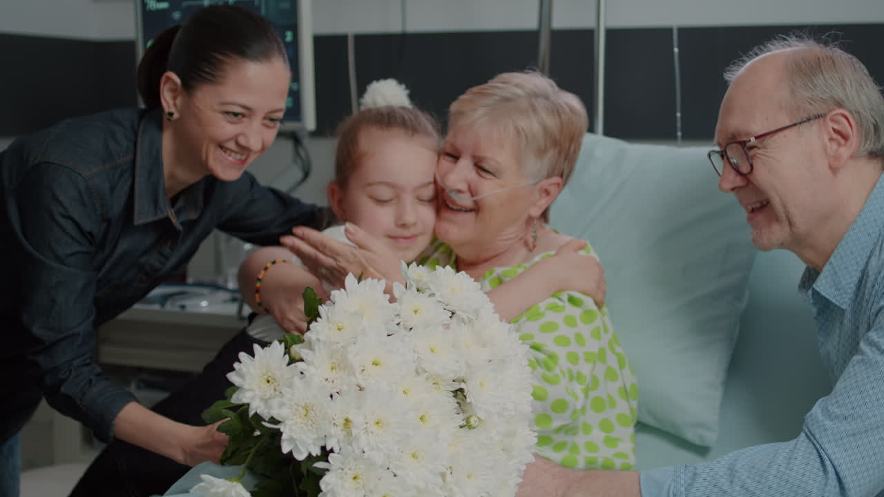 Little girl running to hug and give flowers to aged patient in hospital ward bed