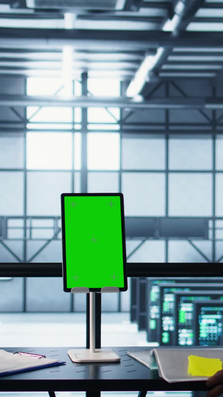 Vertical video Programmers in data center using mockup tablet, observing equipment analytics