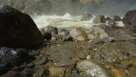 low pov dolly forward shot over wet stones at moul falls, waterfall steam