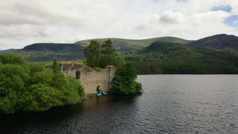 Alturas-Etéreas:-Vista-Aérea-De-Los-Frondosos-Bosques-Y-Las-Tranquilas-Aguas-Del-Lago-An-Eilein-Y-Un-Antiguo-Castillo,-Ubicado-En-Los-Cairngorms-En-Las-Tierras-Altas-De-Escocia,-Escocia