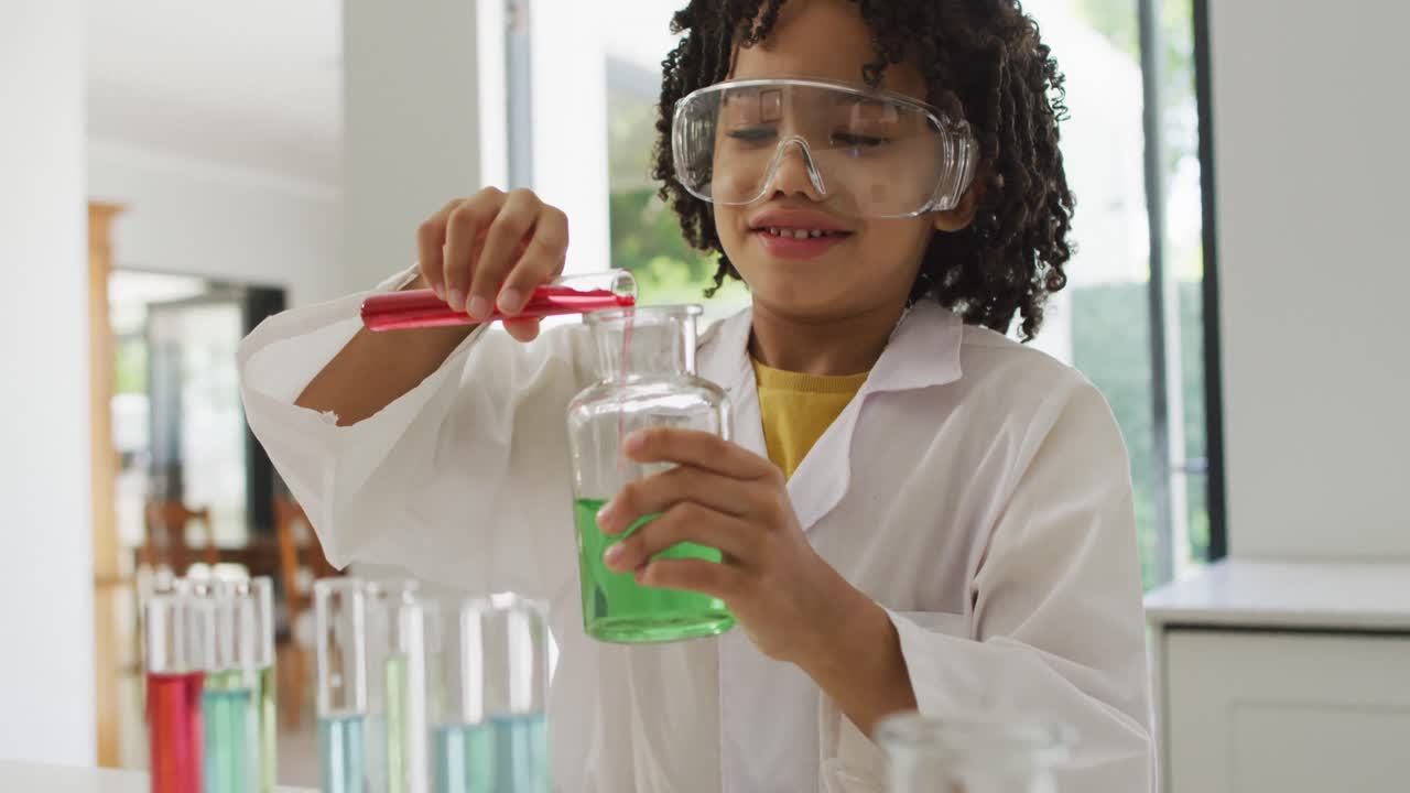 feliz muchacho biracial haciendo experimentos de química, sosteniendo un tubo de ensayo