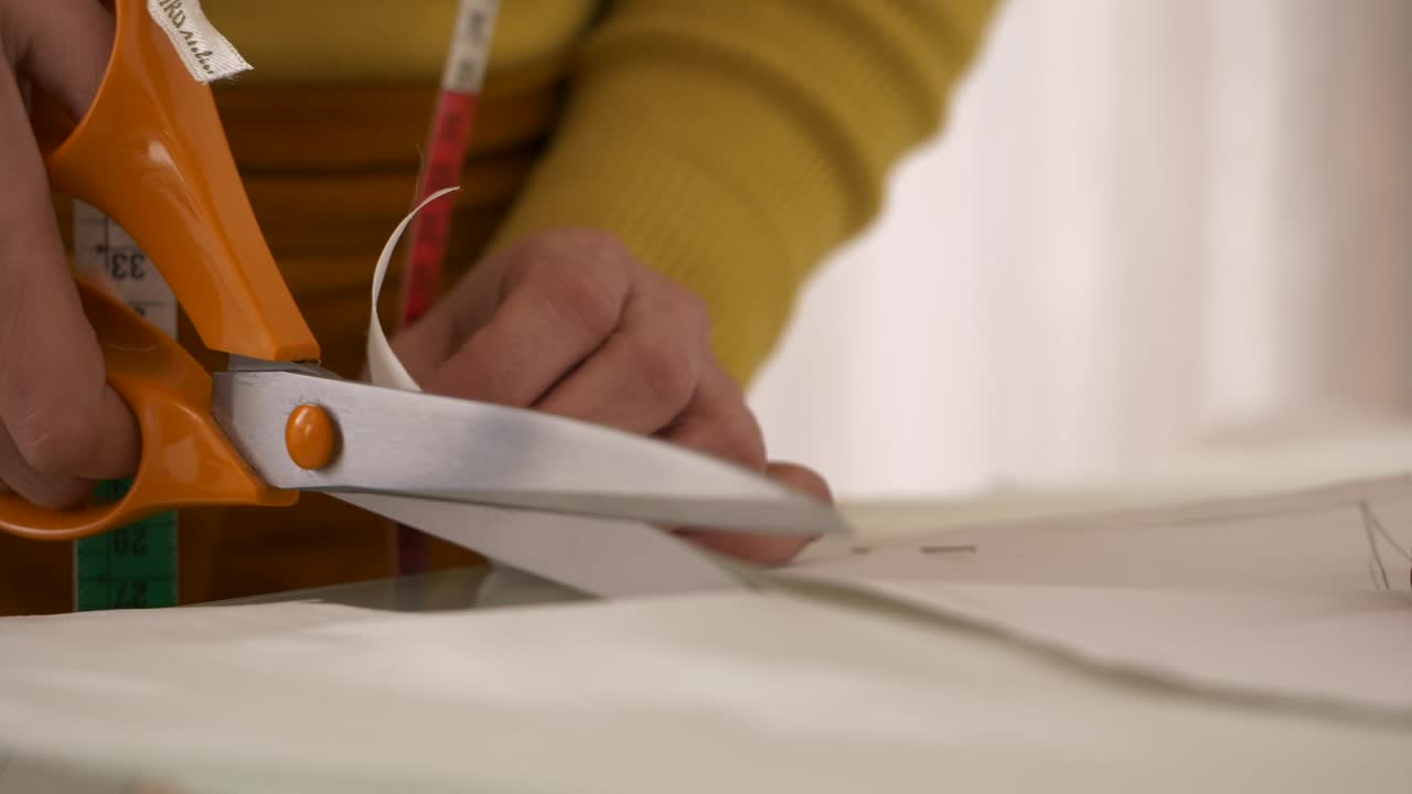 sastre cortando papel con patrón de costura sujetando el peso en su lugar, cierre a cámara lenta