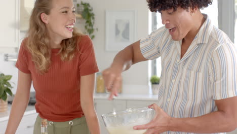 in kitchen, diverse couple mixing ingredients for dessert with fresh strawberries nearby, at home