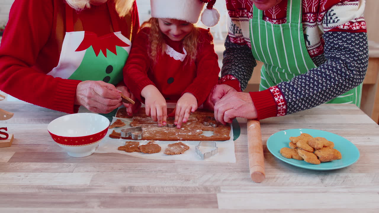 abuelos mayores con nieta niña preparando, cocinando galletas en casa cocina navideña