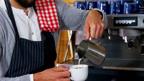 waiter pouring milk in coffee