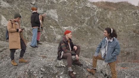 grupo de amigos adolescentes vestidos con ropa de invierno hablando y usando un smartphone en la montaña