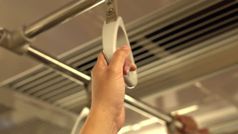 Short-person's-hand-holding-safety-handle-on-the-subway-train