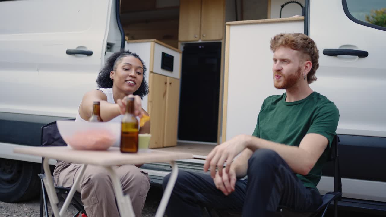People enjoying beer and food near a van