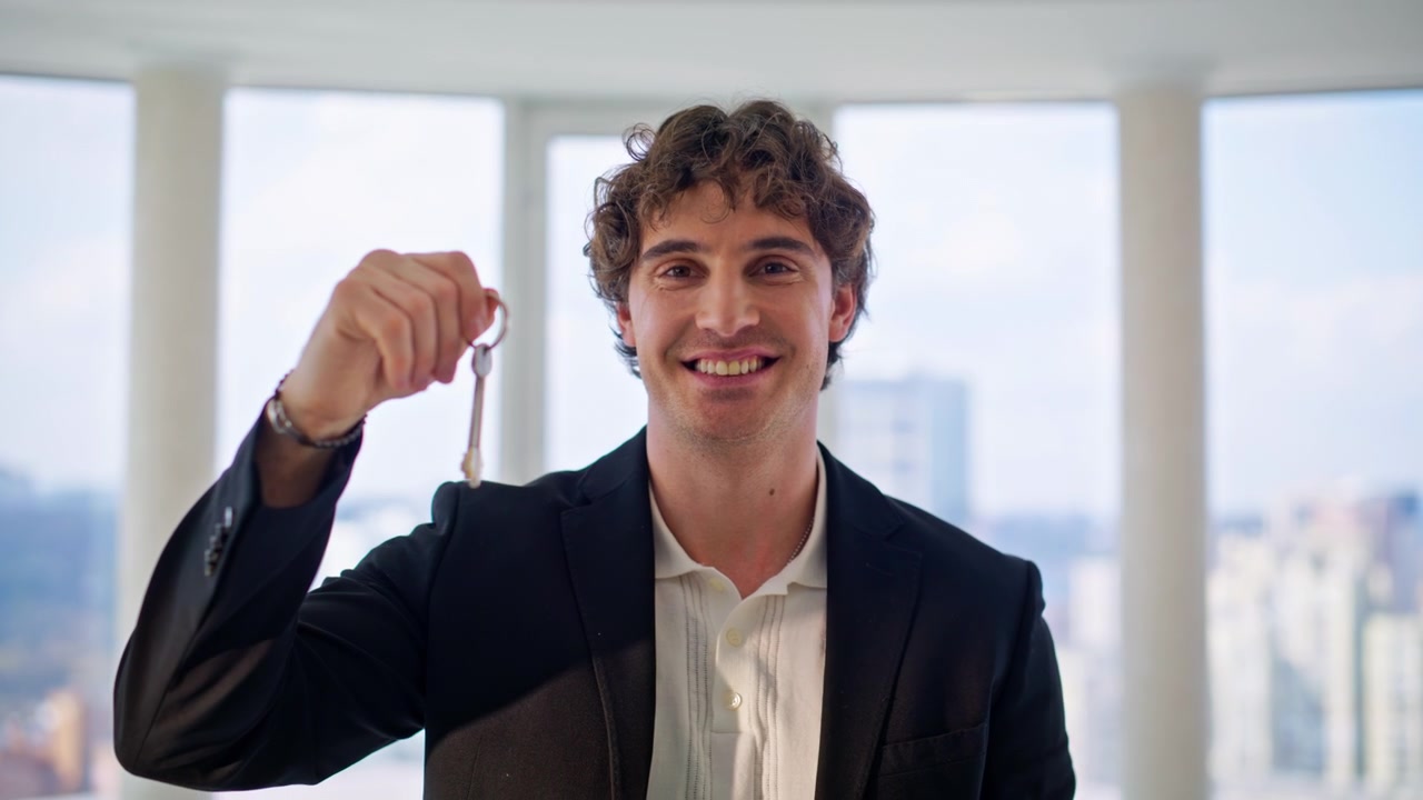 Agente imobiliário feliz mostrando chaves. Corretor sorridente segurando chaves de uma nova casa