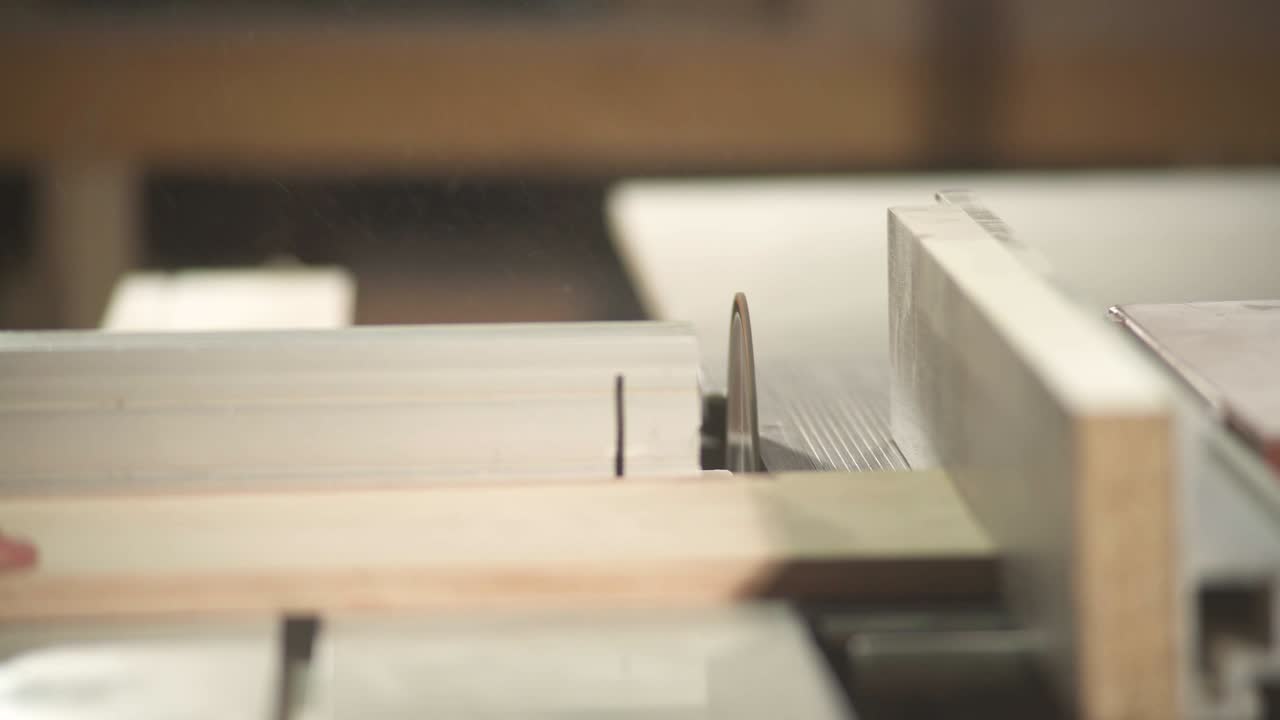A front view of a table circular saw cutting a plywood board at a right angle