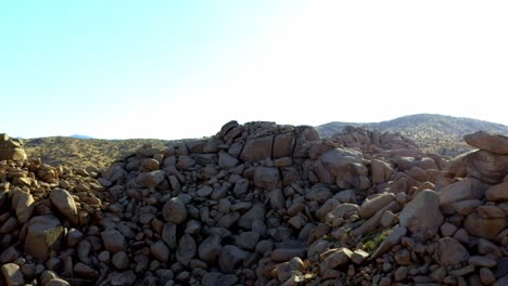 disparo de drones volando hacia unas rocas grandes en el desierto de pioneertown, california