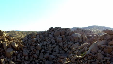 drone shot flying towards some large rocks in the desert of pioneertown, california