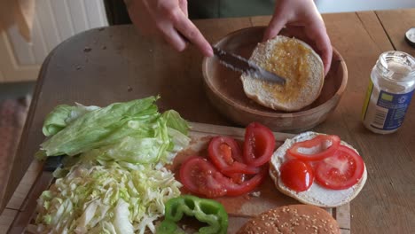 cook preparing a delicious veggie burger adding gherkin sauce in 4k slow motion