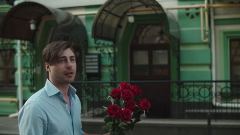 Closeup-man-throwing-red-roses-at-paved-street.-Man-smelling-roses-at-street