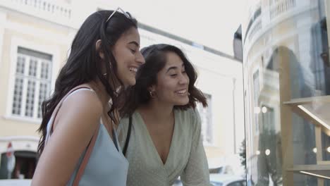 two friends pointing at shop window and discussing product