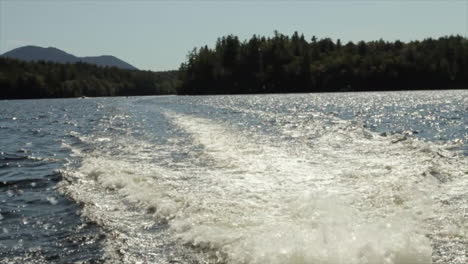 this is a shot of water churning from behind a boat as it travels around saranac lake