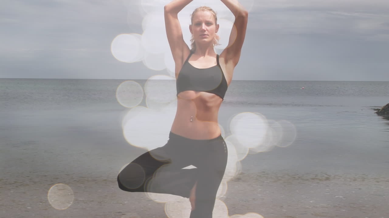 animación de puntos de luz sobre mujer caucásica practicando yoga en la playa.