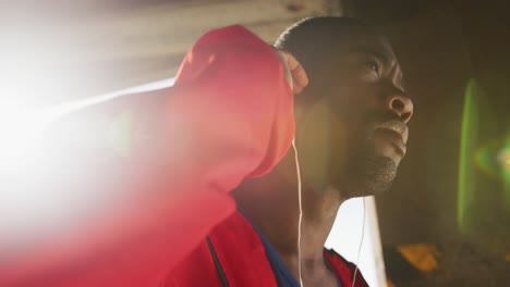 Focused-african-american-man-putting-earphones-on-before-exercising-outdoors