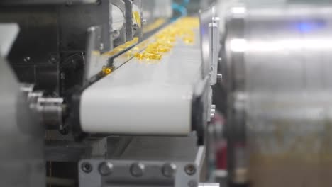 4k video of vitamins moving onto a conveyor belt towards the dryer drums on an assembly line