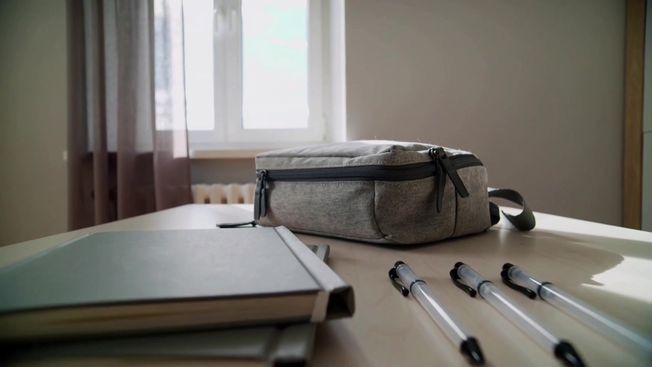 Sliding camera tracking frames moving forward, shifting right on table by window showing gray pouch