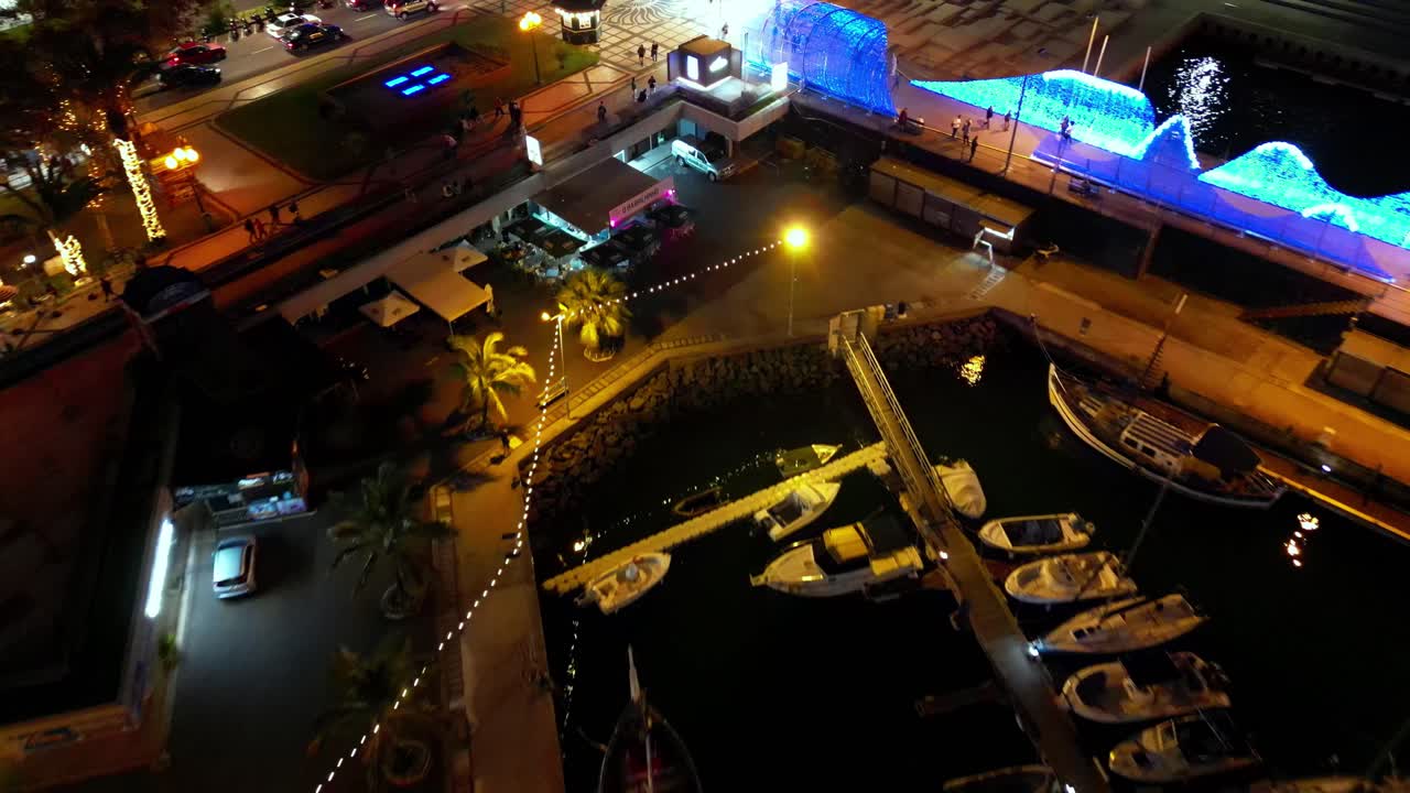 이것은 밤에 마데이라의 선착장을 보여주는 높이를 얻는 역방향 샷으로 짙은 황금색 느낌을 발산합니다.