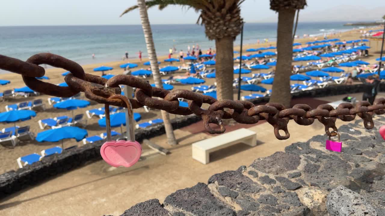 Heart padlocks on rusty chain in Puerto del Carmen beach walk