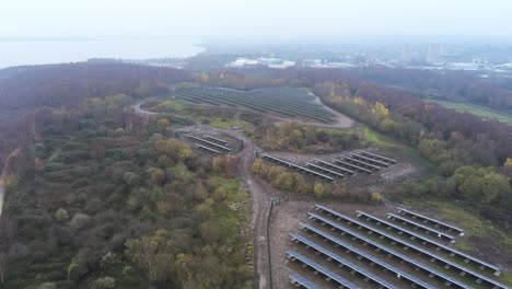 Vista-Aérea-De-Las-Filas-De-La-Matriz-De-Paneles-Solares-Brumoso-Campo-Del-Bosque-De-Otoño-Tiro-Alto-En-Aumento