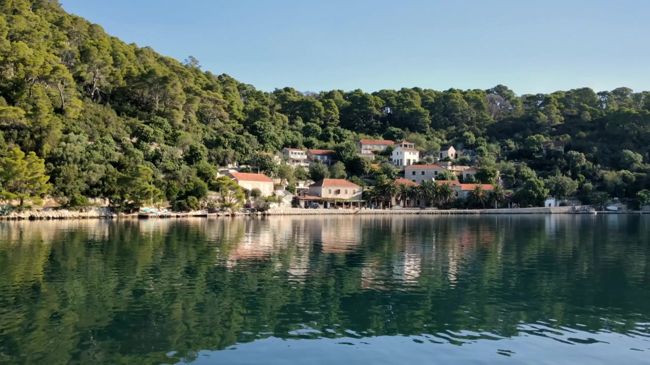 Piccolo villaggio europeo in riva al mare circondato da montagne verdi, Europa meridionale.