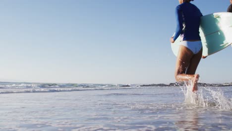 African-american-couple-running-with-surfboards-on-the-beach