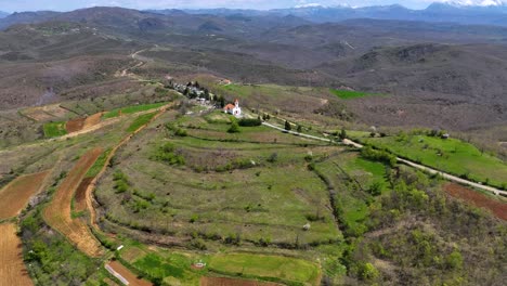 small white church on top of a hill with cemetery behind