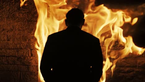 a man in a suit stands before a wall of fire