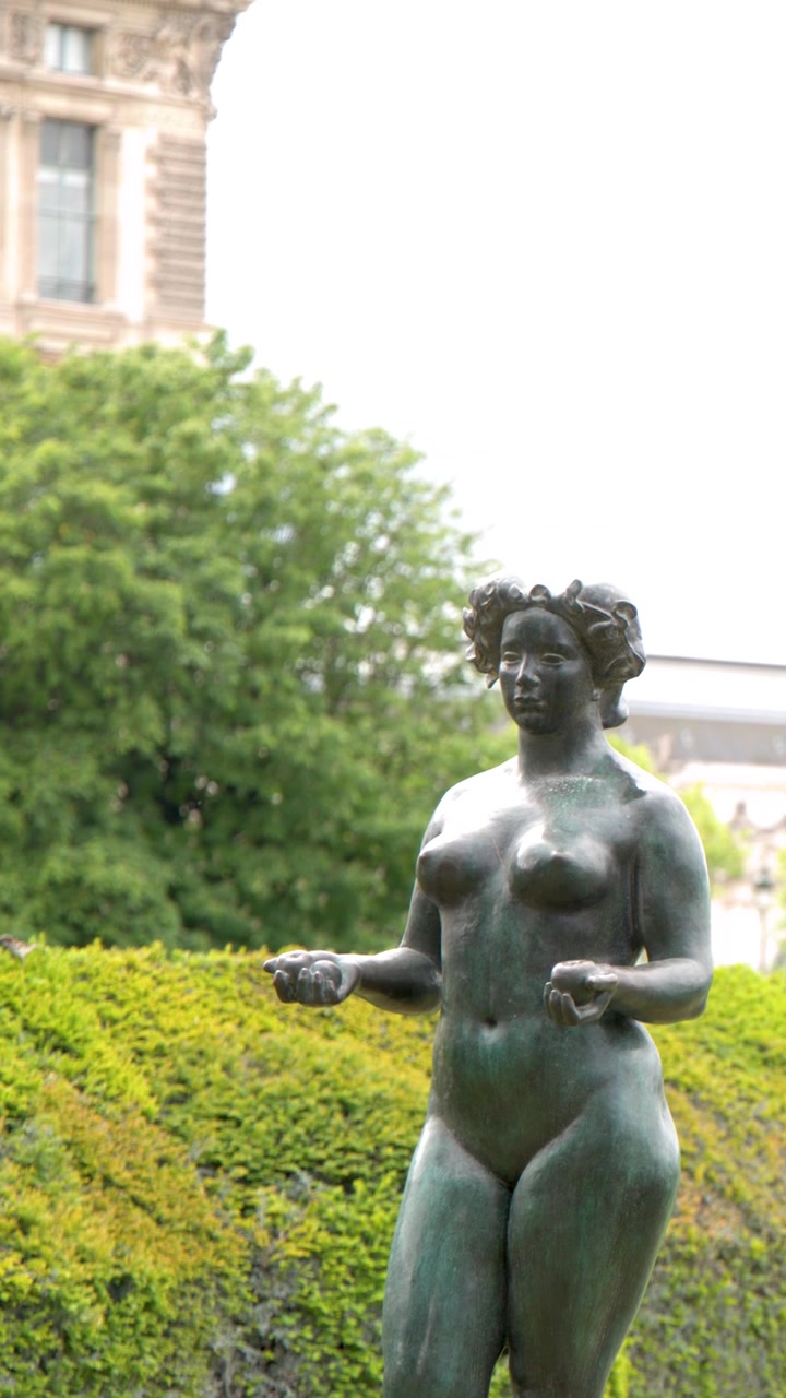 Inquadratura media di una scultura femminile in bronzo contro siepi verdi nel Giardino delle Tuileries, Parigi.