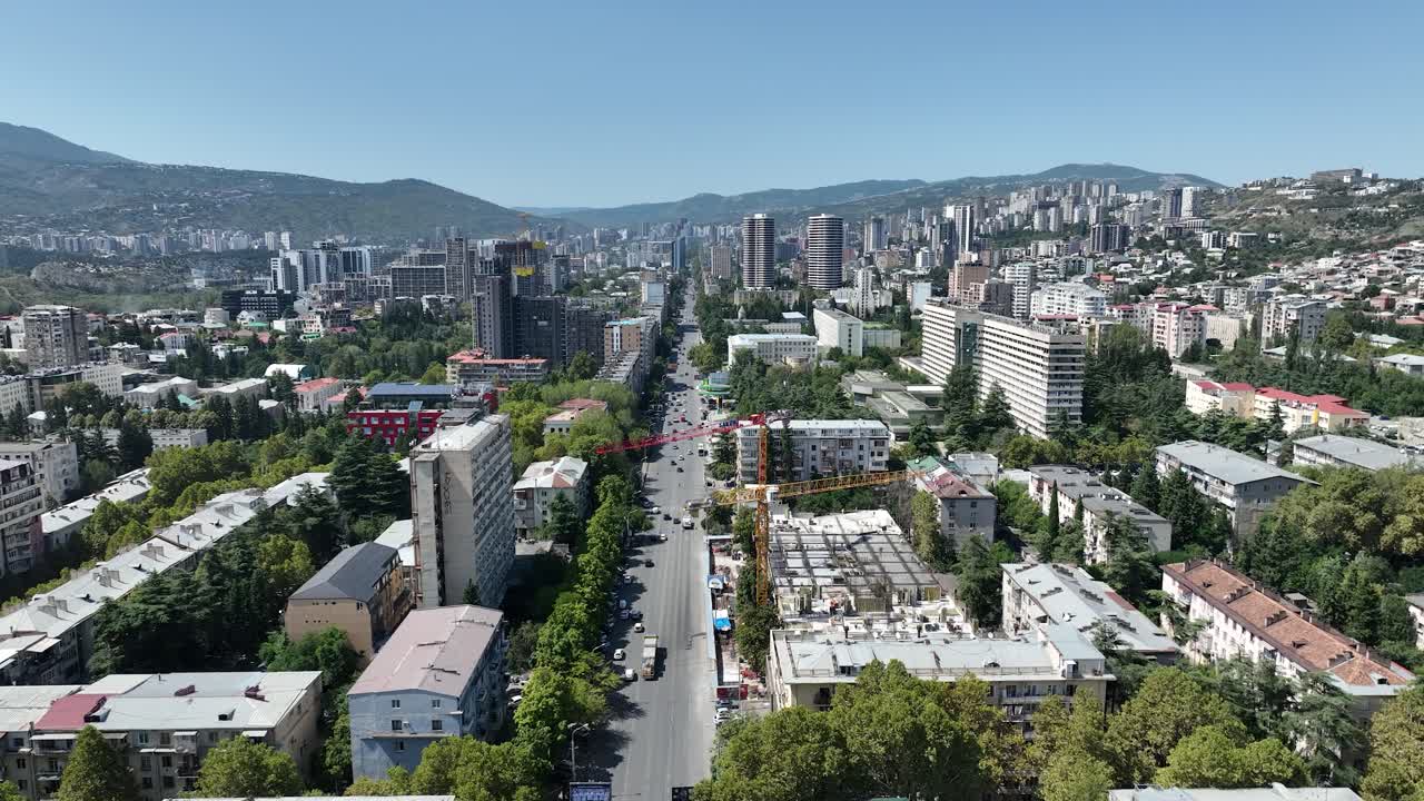 vista aérea de un paisaje urbano con filas de edificios y áreas residenciales, enmarcadas por montañas en el fondo