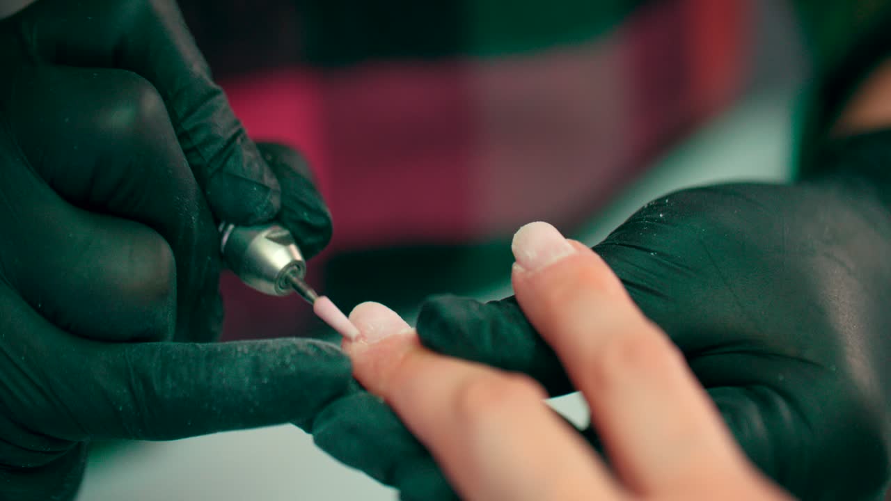 un manicurista muele las uñas con una máquina de manicura