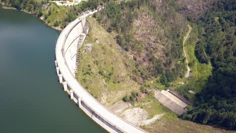 toma aérea de un dron que comienza en un río que atraviesa un dique y revela la ladera de una montaña