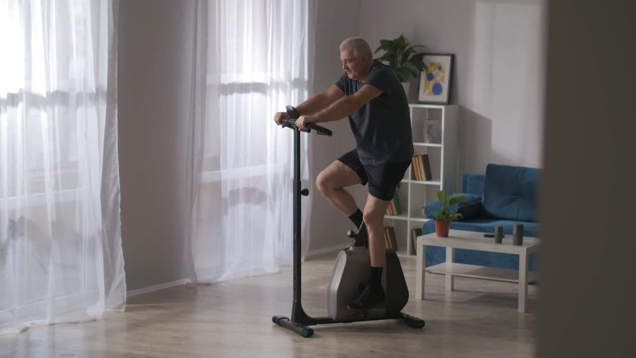 stationary bicycle for home sport equipment for caring health adult man is training alone in living room fitness and sport activities