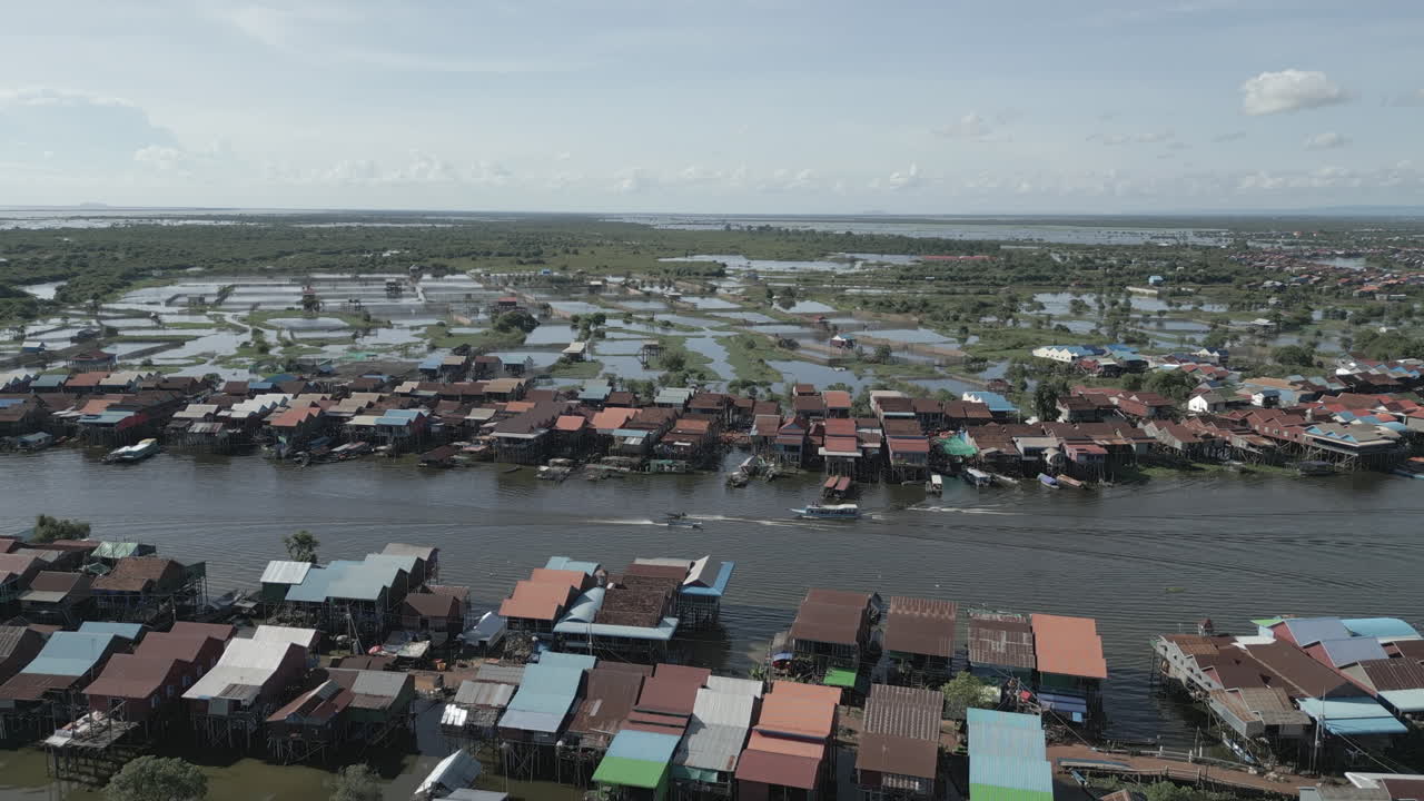 Aerial video of an expansive Tonlé Sap floating village seen from above, with rows of stilt houses lining both sides of the river
