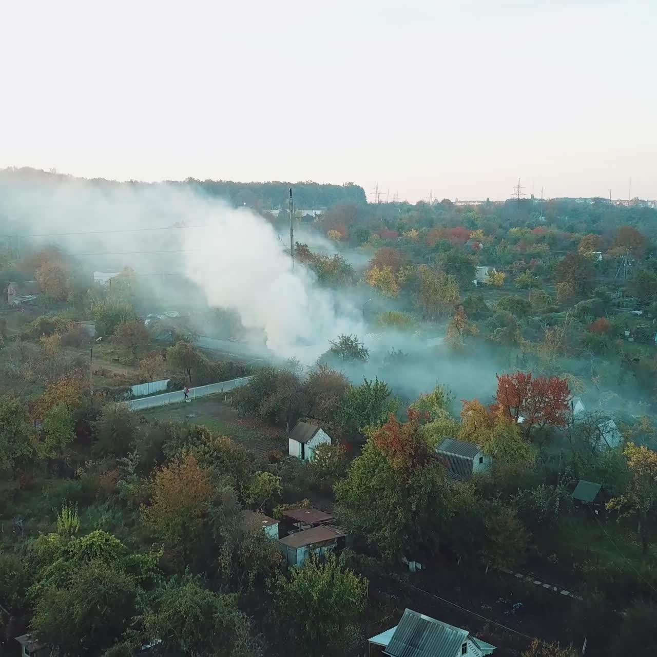 smoke from the fire is filling the space above the private sector of the suburb in the summer. Aerial view