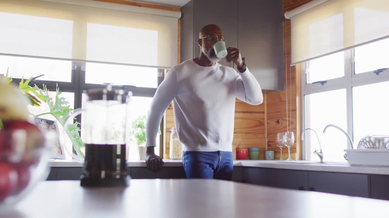 un anciano afroamericano pasa tiempo en una cabaña de madera y bebe café, en cámara lenta.