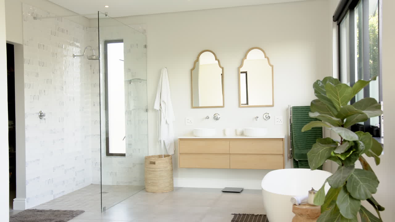 Modern bathroom with glass shower, double sinks, and large bathtub