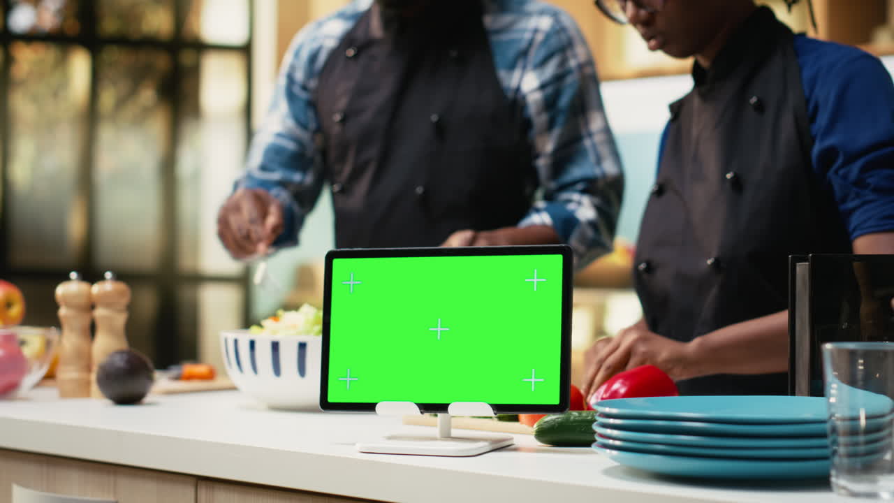 Chefs preparing salad with tablet showing green screen