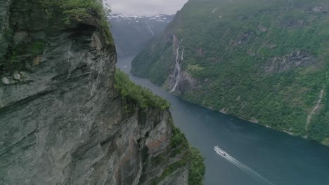 aerial slomo shot flying towards the geiranger fjord with a moving boat and the seven sisters waterfall in the background