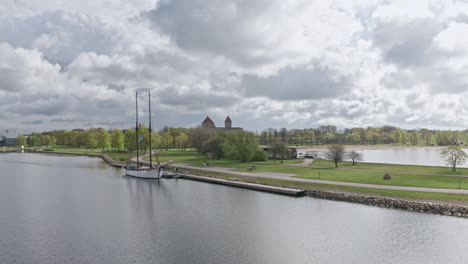 Altes-Segelboot-Vor-Anker-Im-Hafen-Und-Eine-Mittelalterliche-Festung-Im-Hintergrund